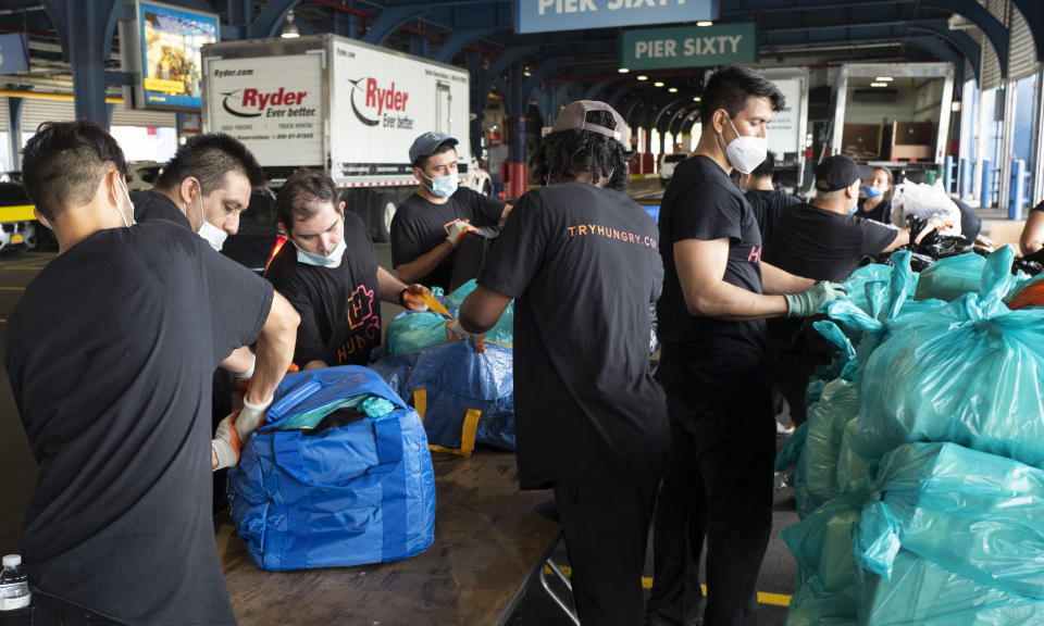 Workers load prepackaged meals into insulated containers for delivery to needy families in New York on Tuesday, July 7, 2020. Catering startup HUNGRY is feeding the stuck-at-home elderly and low-income kids, reaching 10,000 homes a day. (AP Photo/Mark Lennihan)