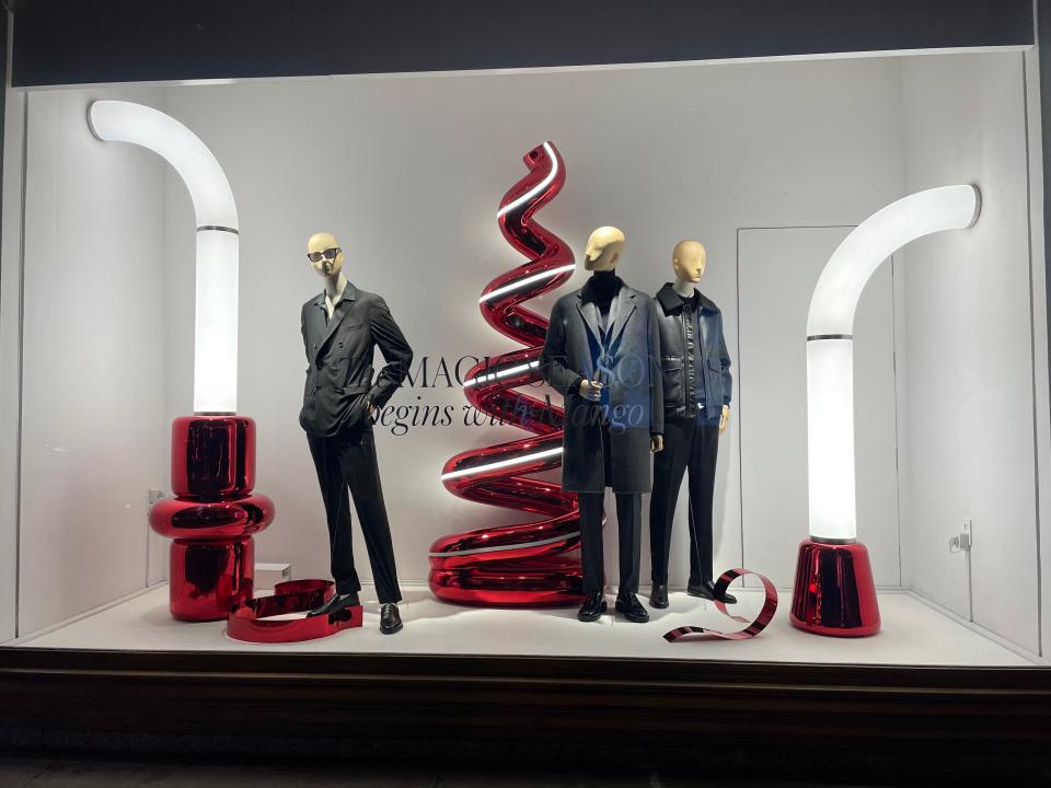 the holiday window at Mango features red chrome sculptures and mannequins wearing black clothes