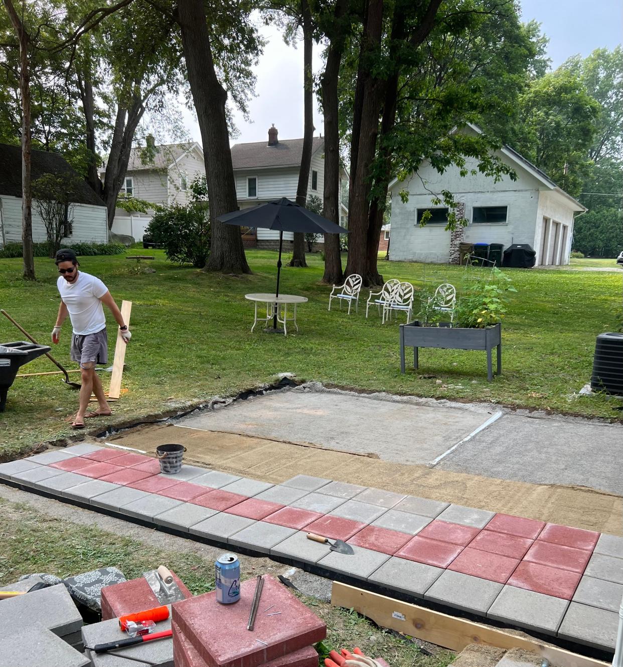 Aaron Bennett works on screeding the sand while Tess lays down pavers.