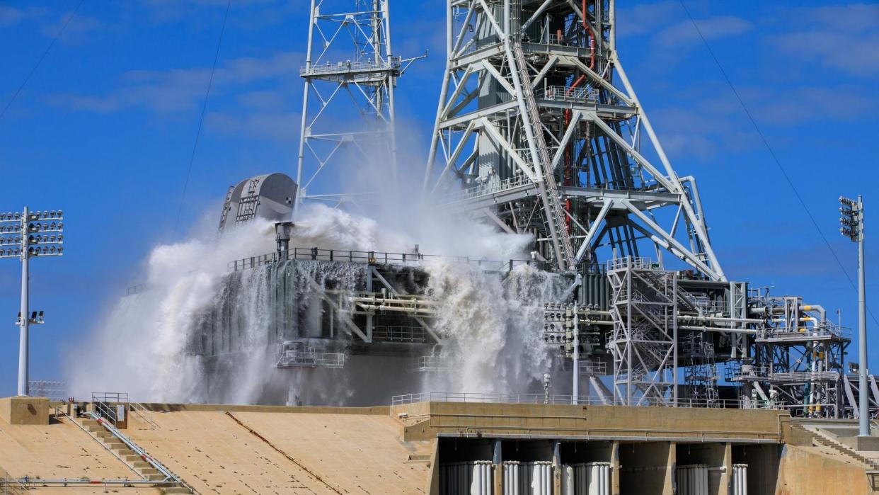  Water splashes and froths at the base of a large metal tower. 
