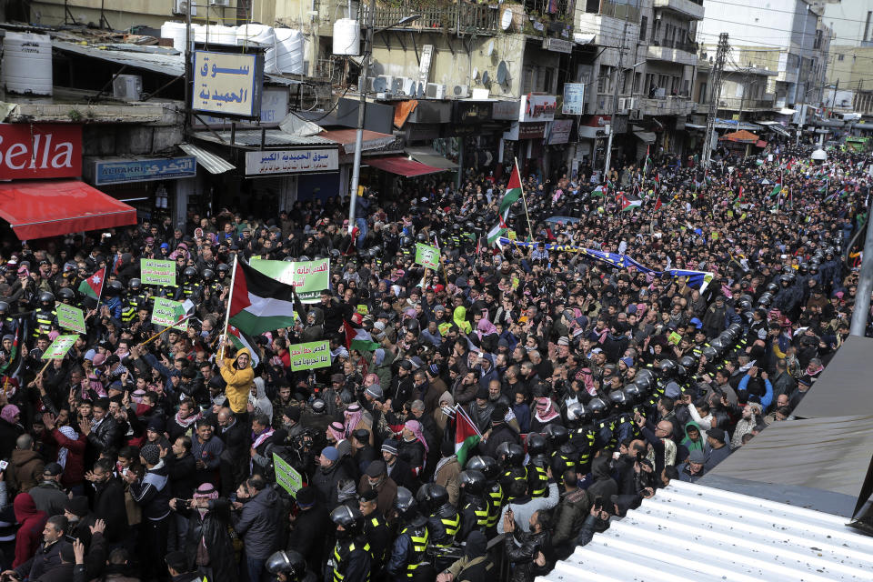 Protesters carry Jordanian and Palestinian flags and slogans during a protest against the Middle East peace plan proposed by U.S. President Donald Trump, in the center of Amman, Jordan, Friday, Jan. 31, 2020. (AP Photo/Raad Adayleh)