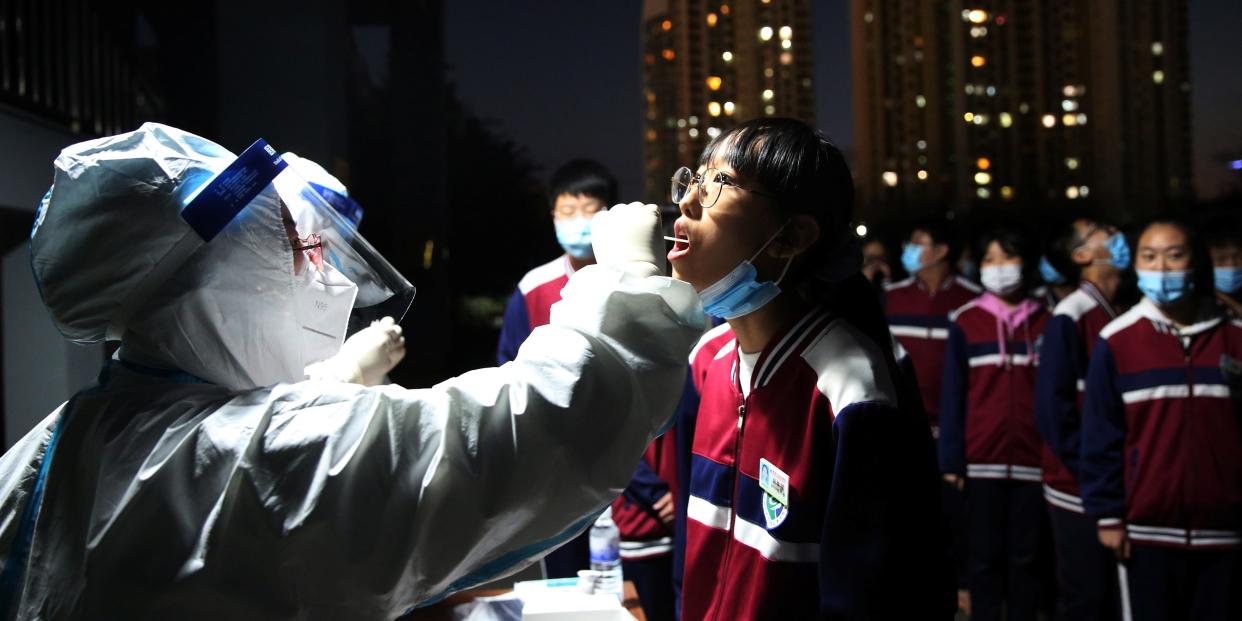 A medical worker in protective suit collects a swab from a middle school student for nucleic acid testing, following new cases of coronavirus disease (COVID-19) in Qingdao, Shandong province, China October 12, 2020. Picture taken October 12, 2020. China Daily via REUTERS ATTENTION EDITORS - THIS IMAGE WAS PROVIDED BY A THIRD PARTY. CHINA OUT.