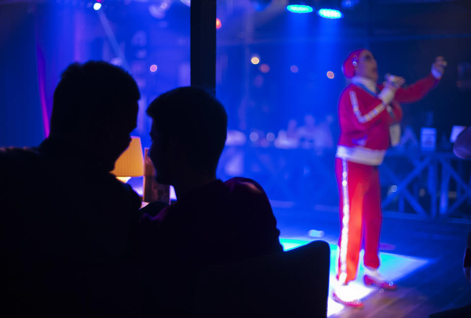 In this photo taken Saturday, Feb. 8, 2014, two men watch a performance at the Mayak cabaret, the most reputable gay club in Sochi, Russia, host to 2014 Winter Olympics. Russia adopted a law last year, prohibiting vaguely defined propaganda of non-traditional sexual relations and pedophilia. The legislation makes it illegal to disseminate information to children even if it merely shows that gay people are just like everybody else. At Mayak, packed on Saturday night, gay men and women steered away from discussing the law, preferring to enjoy life, closeted as it is. About a hundred people were chatting at the bar, sitting in armchairs or dancing. Couples were sharing kisses. Everyone was waiting for the club's specialty: a drag show. At 1.30 a.m. on Sunday, the music stopped and the show began. (AP Photo/David Goldman)