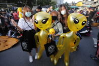 Protesters flash three-finger protest gestures while holding balloons shaped like aliens - to mock accusations that foreigners fund and direct their movement - during a rally Friday, Nov. 27, 2020 in Bangkok, Thailand. Pro-democracy demonstrators are continuing their protests calling for the government to step down and reforms to the constitution and the monarchy, despite legal charges being filed against them and the possibility of violence from their opponents or a military crackdown. (AP Photo/Sakchai Lalit)