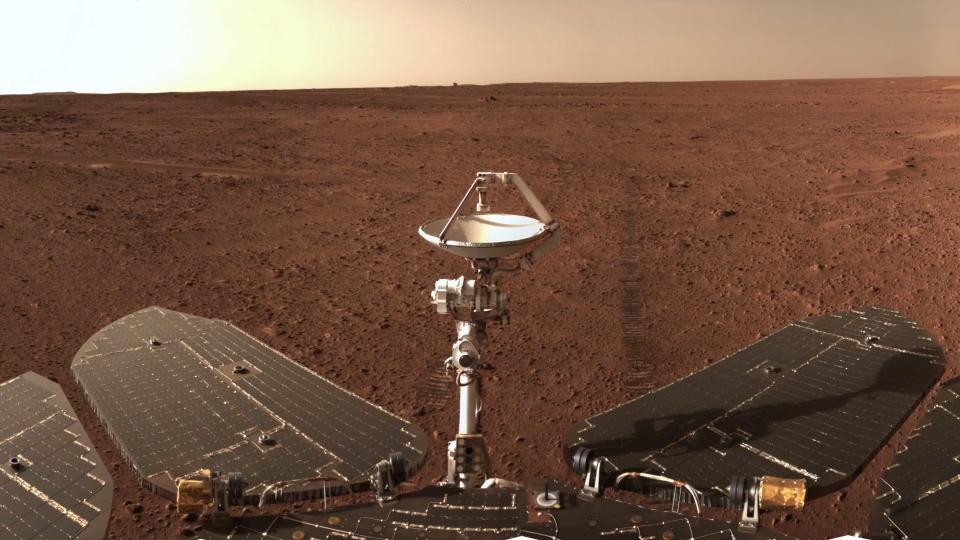  Closeup selfie taken by a mars rover, with red dirt and the horizon in the background. 