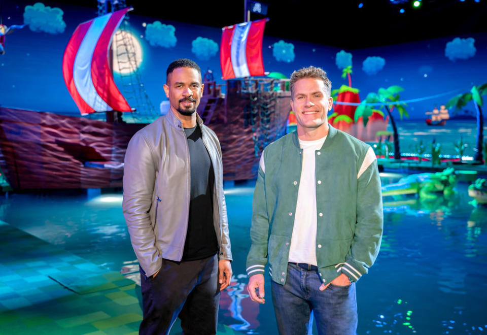 Hosts Damon Wayans Jr., and Kyle Brandt stand in front of the Frogger course