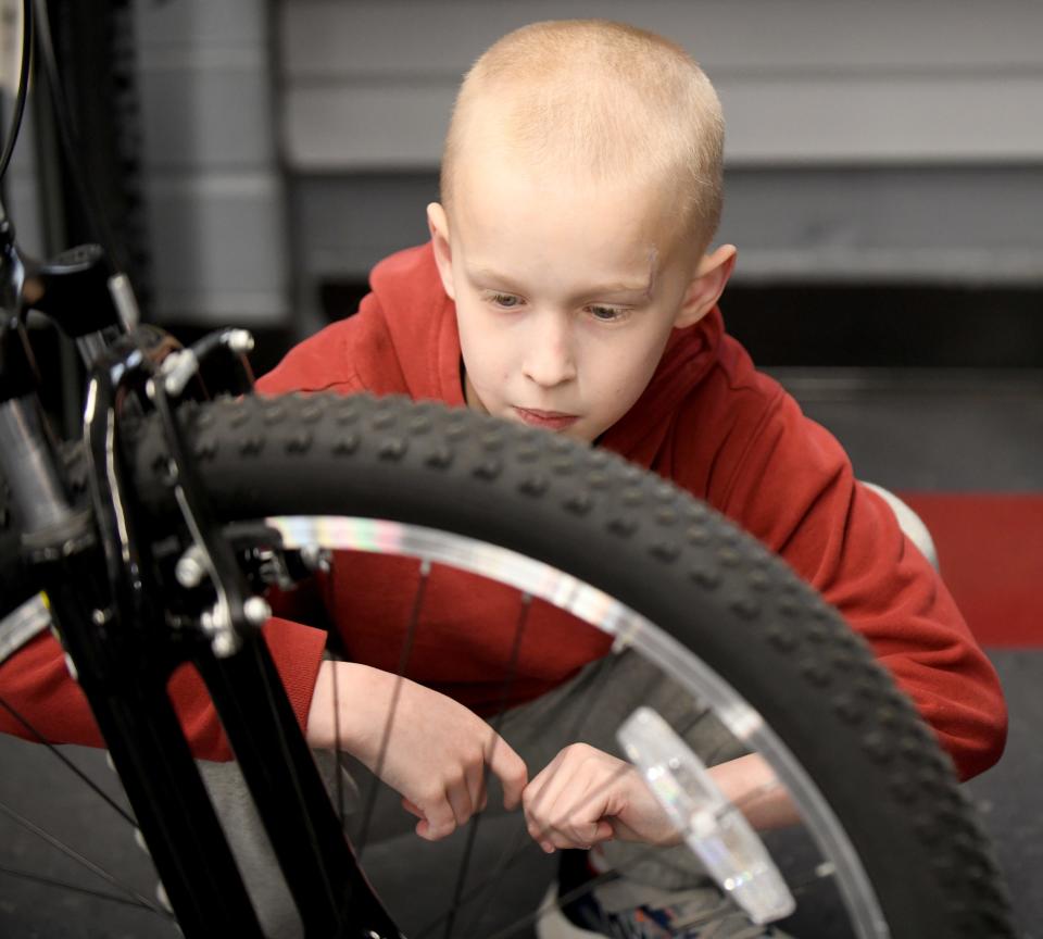 Jordan Owens, 9, who was injured in a Labor Day bicycle accident, checks out his new bike at Ernie’s Bike Shop in North Canton. An anonymous donor bought it for the Plain Township boy in the hope he would live life "with caution but no fear."