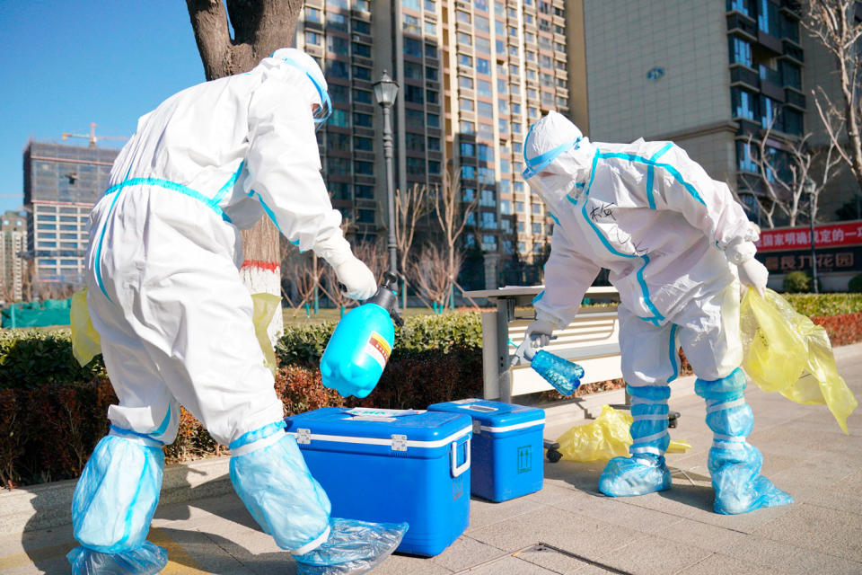 Workers disinfect containers of coronavirus test samples outside of a residential neighbourhood in Shijiazhuang. Source: AP