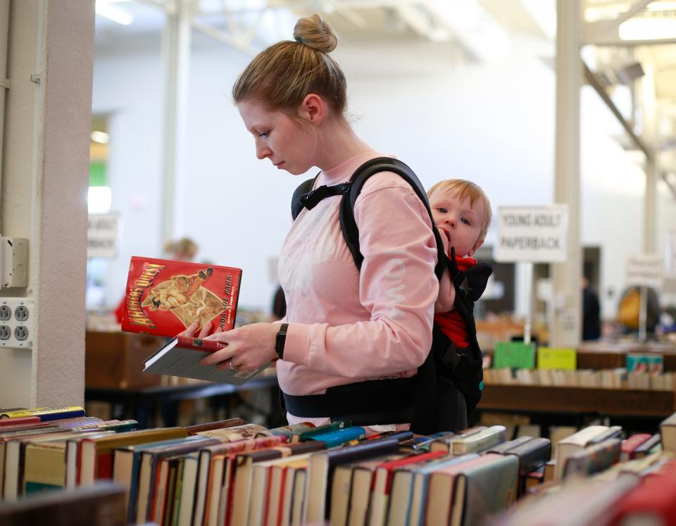 Katelyn Dunn, a book lover from Mount Pleasant, peruses books as her 10-month-old son, Archer, rides along during the annual Planned Parenthood book sale on Thursday, April 21, 2022, at the 4-H building at the Iowa State Fairgrounds in Des Moines.