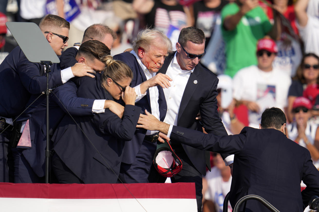 Trump is helped off the stage by Secret Service.