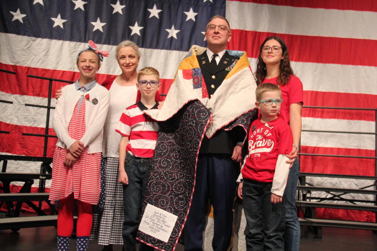 Peter Meis poses for a photo with his family after receiving a Quilt of Valorfrom the Perry Piecemakers Quilt Guild during the Veterans Day program on Friday, Nov. 10, 2023, at Perry Performing Arts Center.