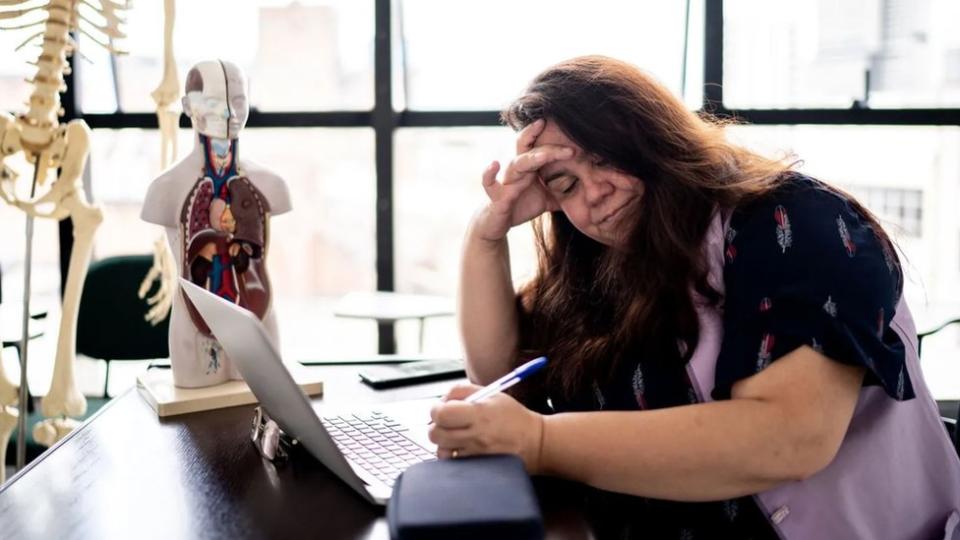 Una mujer frente a un escritorio se toma la cara. (Getty Images)