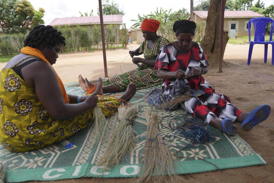 Women survivors weave grass and thread bowls outside their home at Mybo reconciliation village in Nyamata, in Kigali, Rwanda Friday, April 5, 2024. More than half the residents of this reconciliation village are women, and their projects — which include a basket-weaving cooperative as well as a money saving program — have united so many of them that it can seem offensive to inquire into who is Hutu and who is Tutsi. (AP Photo/Brian Inganga)