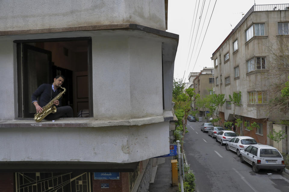 Mohammad Maleklee, 23, of the National Orchestra of Iran and Tehran Symphony, plays saxophone from his window, during mandatory self-isolation due to the new coronavirus disease outbreak, in Tehran, Iran on Wednesday, April 8, 2020 photo. With performance halls closed, musicians find performance spaces wherever they can. (AP Photo/Ebrahim Noroozi)