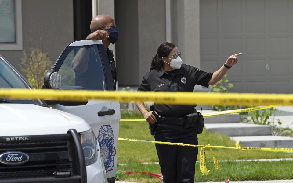 Denver police officers stand outside a house in suburban Denver on Wednesday, Aug. 5, 2020, where five people were found dead after a fire. Three people escaped the fire by jumping from the home's second floor. Investigators believe the victims were a toddler, an older child and three adults. Authorities suspect was intentionally set. Witnesses told firefighters that three people on the second floor of the burning home jumped to safety. A fire department spokesman said the fire's heat pushed back a police officer trying to rescue the people who were on the home's first floor. (AP Photo/Thomas Peipert)