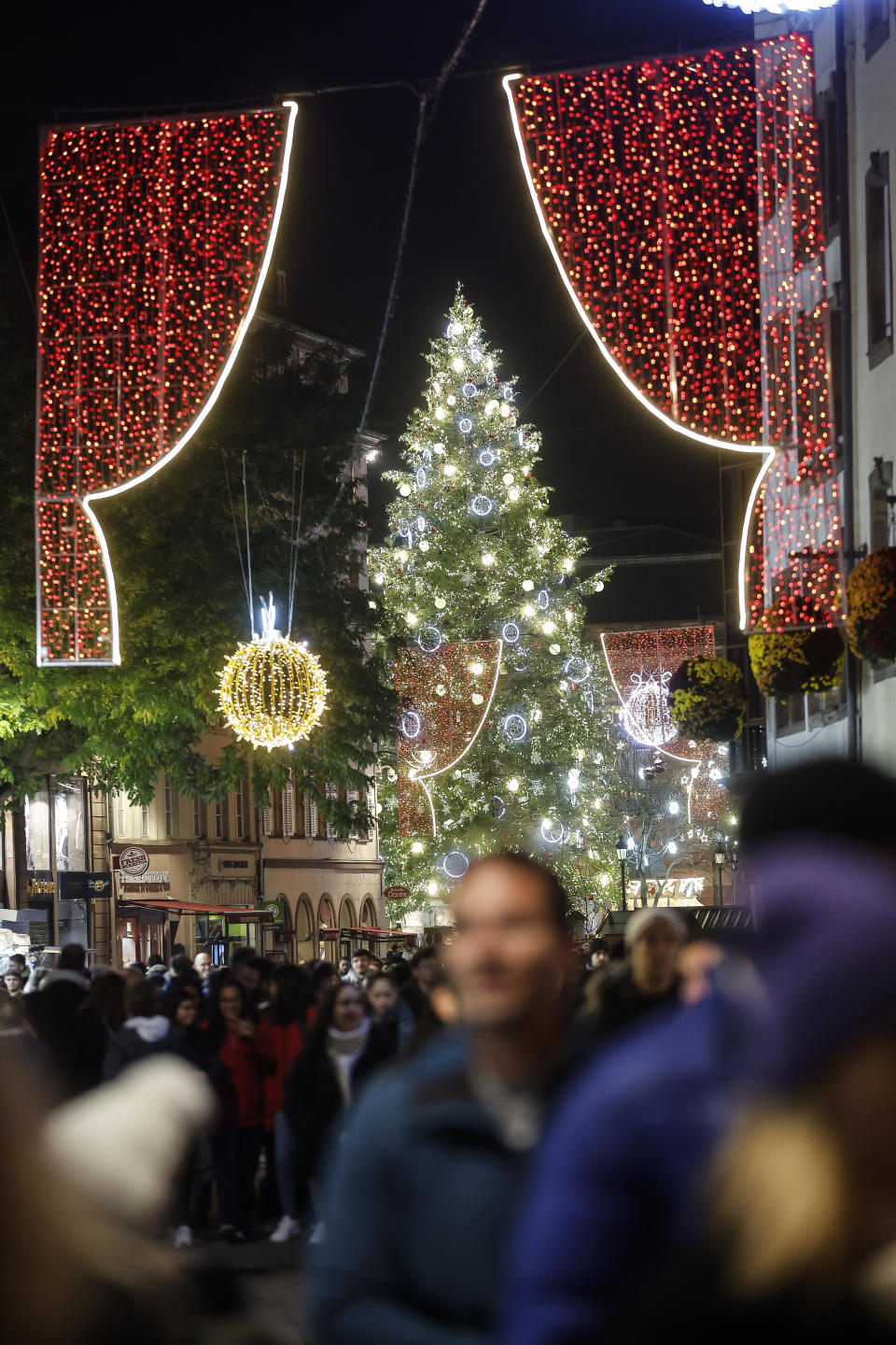 FILE - Visitors stroll around Strasbourg's Christmas market, one of the oldest and biggest Christmas markets in Europe. Strasbourg, eastern France, Nov. 25, 2022. In cities across Europe, officials are wrestling with a choice this Christmas. Dim lighting plans to send a message of energy conservation and solidarity with citizens squeezed by both higher energy costs and inflation or let the lights blaze in a message of defiance after two years of pandemic-suppressed Christmas seasons, creating a mood that retailers hope loosen holiday purses. (AP Photo/Jean-Francois Badias, File)