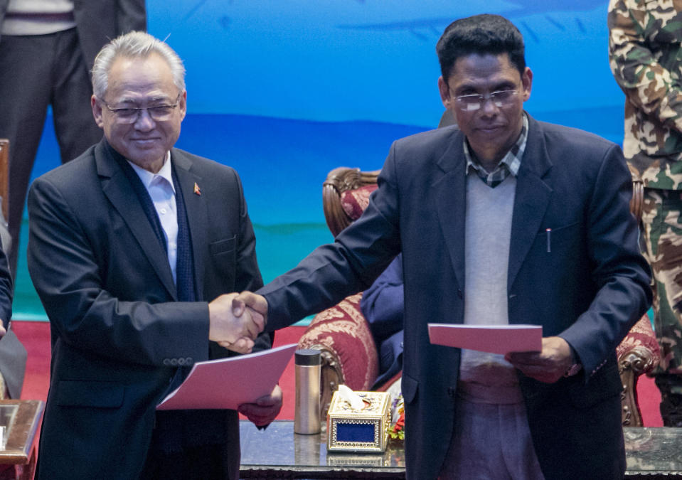 Nepalese Home Minister Ram Bahadur Thapa, left, and the spokesperson of the Nepal Communist Party group Khadga Bahadur Bishwakarma shake hands during a signing of peace agreement in Kathmandu, Nepal, Friday, March 5, 2021. The leader of the small rebel group Netra Bikram Chand , who is better known by his guerrilla name Biplav, merged out of hiding on Friday after the government lifted a ban on his group so it could take part in the public signing of the peace agreement. This group had split from the Maoist Communist party, which fought government troops between 1996 and 2006, when it gave up its armed revolt, agreed to U.N.-monitored peace talks and joined mainstream politics. (AP Photo/Niranjan Shrestha)