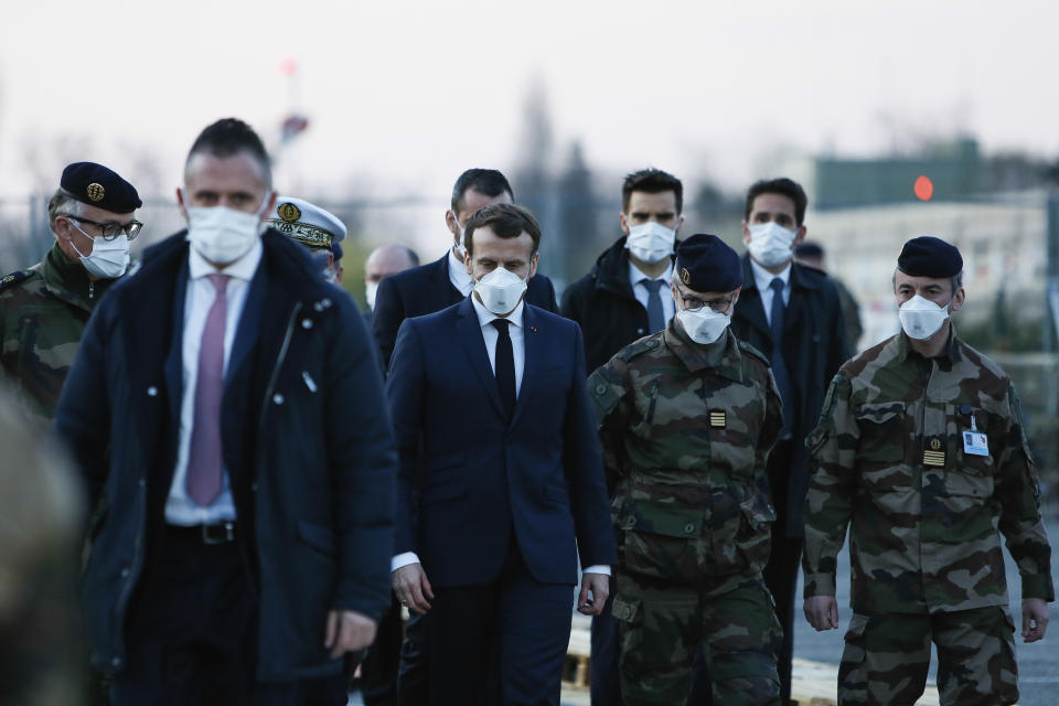 French President Emmanuel Macron, center, wears a face mask as he visits the military field hospital in Mulhouse, eastern France, Wednesday, March 25, 2020. French President Emmanuel Macron launched a special military operation Wednesday to help fight the new virus in one of the world's hardest-hit countries. The new coronavirus causes mild or moderate symptoms for most people, but for some, especially older adults and people with existing health problems, it can cause more severe illness or death. (Mathieu Cugnot/Pool via AP)