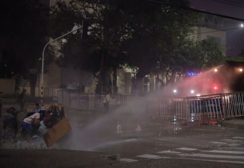 Manifestantes chocan con la policía durante una protesta contra un partido de fútbol de la Copa Libertadores entre el América de Cali y el Atlético Mineiro, que se detuvo varias veces porque los jugadores se vieron afectados por los gases lacrimógenos disparados fuera del Estadio Olímpico Romelio Martínez, en Barranquilla