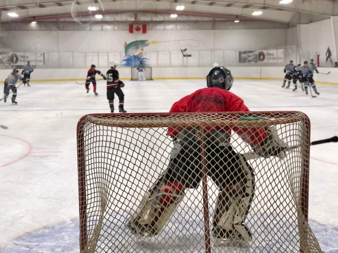 A hockey game at the opening ceremonies for the new ice surface in Délı̨nę, N.W.T.. The community replaced the rink's gravel surface with concrete, and leaders said the upgrade will encourage healthy living and create opportunities for tourism and economic development. (Natalie Pressman/CBC - image credit)