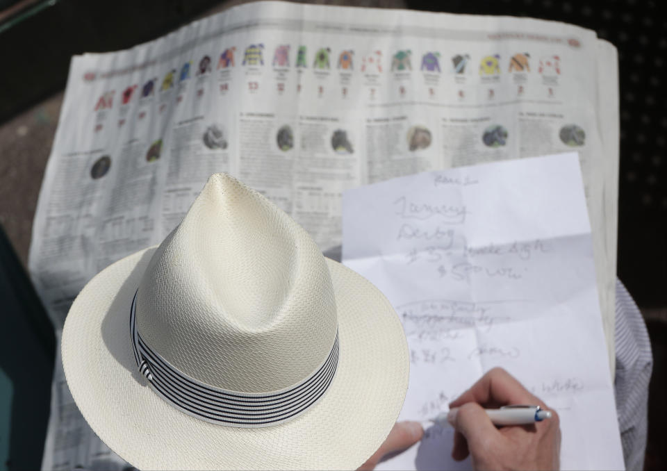 A man looks over a racing program before the 140th running of the Kentucky Derby horse race at Churchill Downs Saturday, May 3, 2014, in Louisville, Ky. (AP Photo/Charlie Riedel)