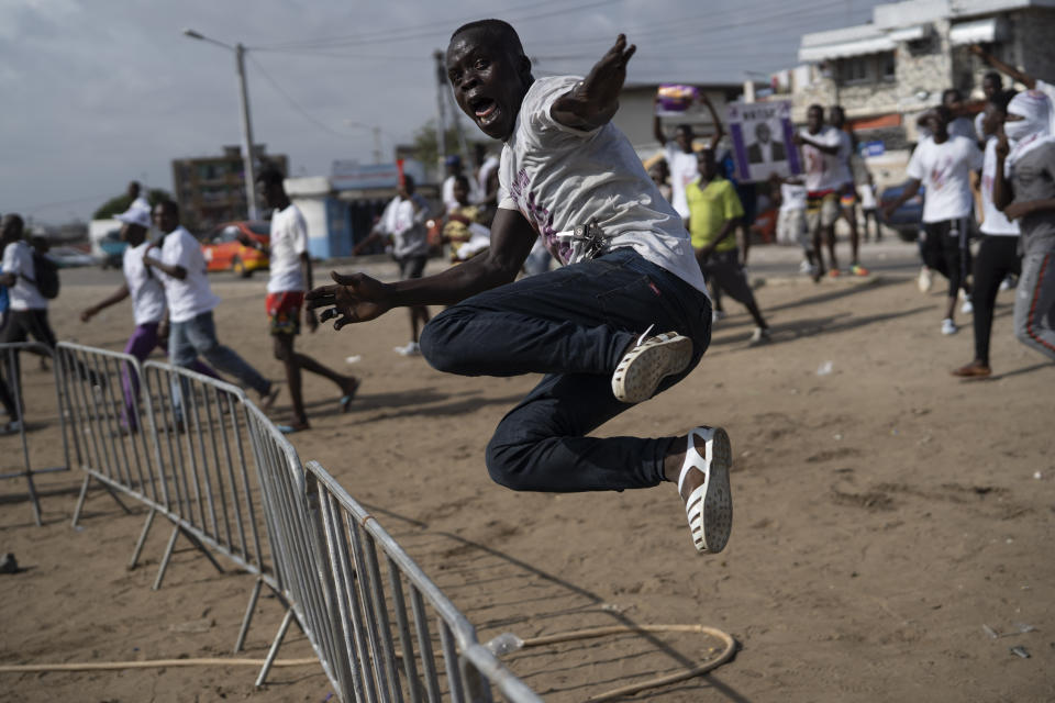 A supporter of the presidential candidate Kouadio Konan Bertin, jumps a fence as he arrives at the final campaign rally in Abidjan, Ivory Coast, Thursday, Oct. 29, 2020. Bertin, known as KKB, has presented his candidacy as an independent candidate for the upcoming Oct. 31 election, and said he would not join the boycott proposed by two main opponents of Ivory Coast President Alassane Ouattara. (AP Photo/Leo Correa)