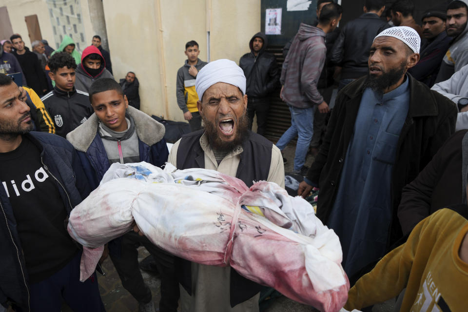 Palestinians chant Islamic slogans while carry the bodies of children killed in the Israeli strikes in the Gaza Strip in front of the morgue at Al Aqsa hospital in Deir al Balah, Gaza Strip, on Sunday, Feb. 18, 2024. (AP Photo/Adel Hana)