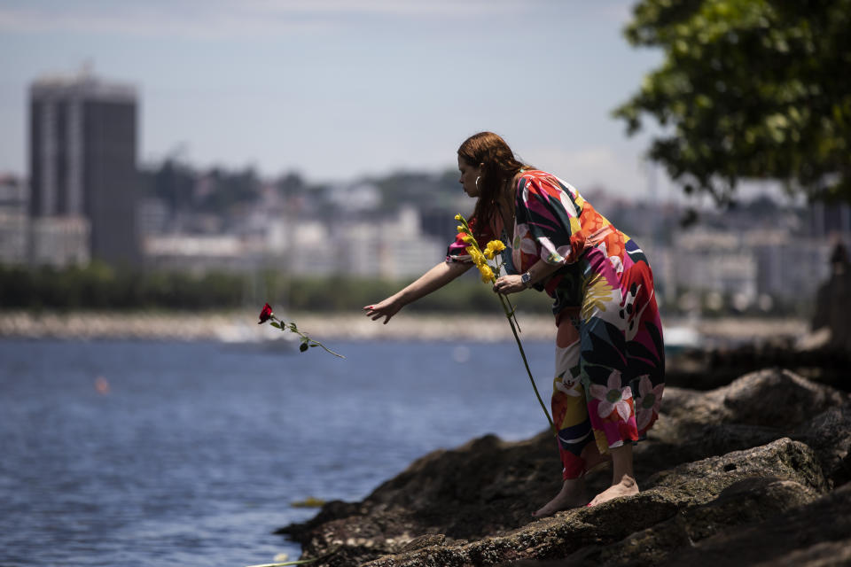 A woman tosses flower offerings into the waters of Urca beach for the African goddess of the sea Yemanja, as part of New Year celebrations in Rio de Janeiro, Brazil, Saturday, Dec. 31, 2022. As the year winds down, Brazilian worshippers honor Yemanja, offering flowers and launching large and small boats into the water in exchange for blessings for the coming year. (AP Photo/Bruna Prado)