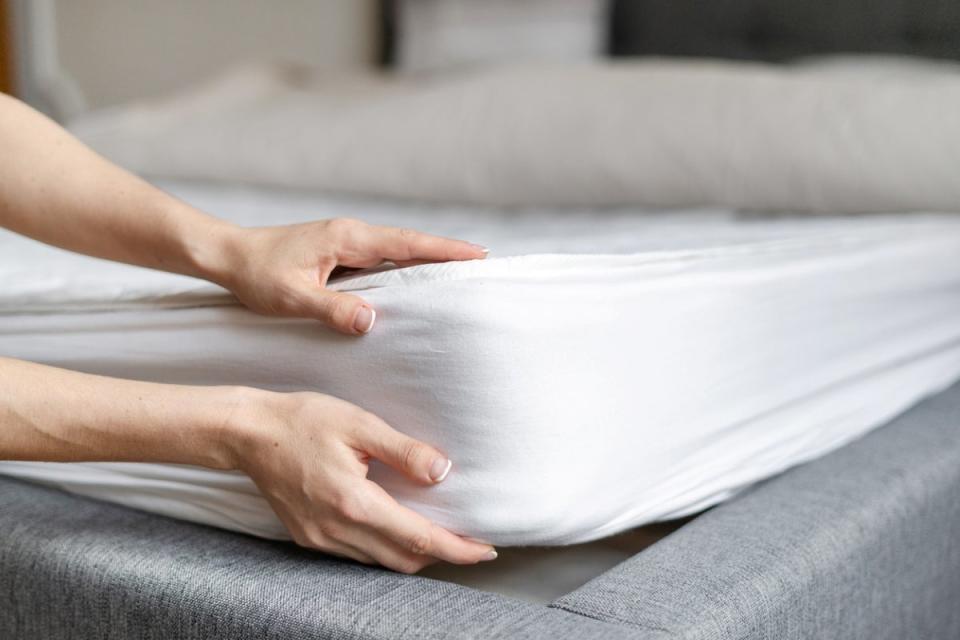 Person tucking fitted sheet around mattress