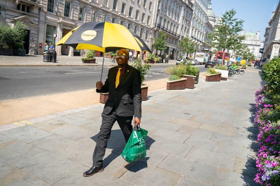 A man uses an umbrella to shade himself from the sun in central London (PA)