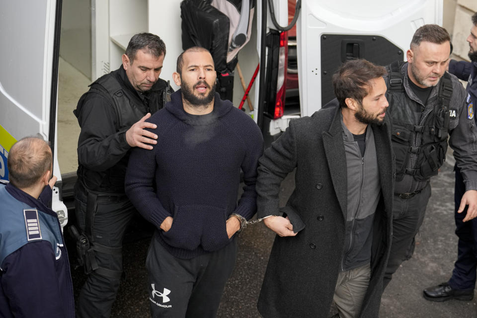 Police officers escort Andrew Tate, center left, handcuffed to his brother Tristan Tate, center right, to the Court of Appeal in Bucharest, Romania, Wednesday, Feb. 1, 2023. Andrew Tate, the divisive influencer and former professional kickboxer who is detained in Romania on suspicion of organized crime and human trafficking appeared at the court in Bucharest on Wednesday to appeal against a second 30-day extension of his detention. His brother Tristan is held in the same case. (AP Photo/Vadim Ghirda)
