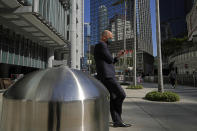 A man wearing a face mask uses mobile phone outside the HSBC headquarters in Hong Kong on Dec. 1, 2021. The bustling, cosmopolitan business hub of Hong Kong may be losing its shine among foreign companies and expatriates with its stringent anti-pandemic rules requiring up to 21 days of quarantine for new arrivals. (AP Photo/Kin Cheung)