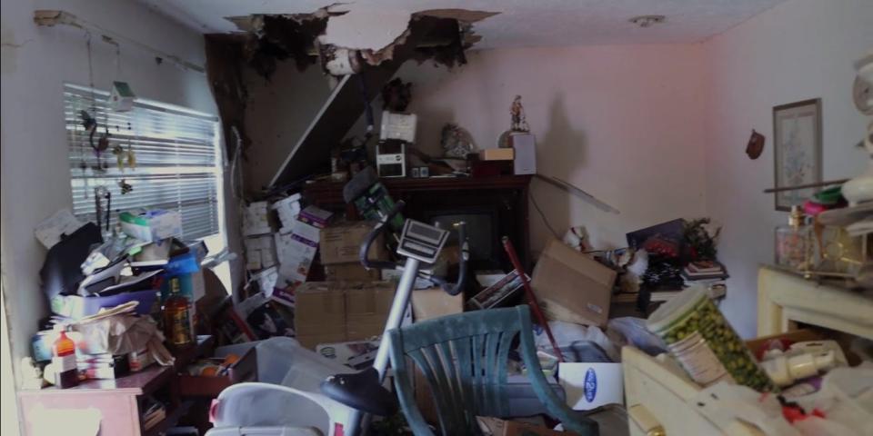 A slightly caved in ceiling in a small room packed with junk