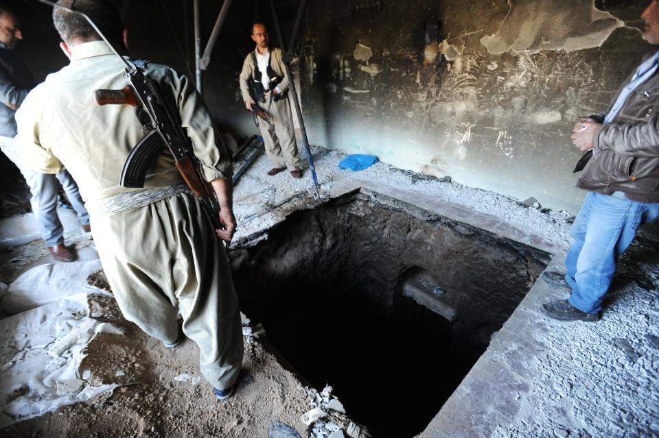 Peshmerga fighters examine the entrance to a 150-meter-long tunnel dug by ISIS