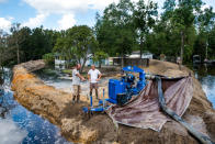 <p>Jason Johnson, left, and homeowner Archie Sanders work to build a temporary levee to hold back floodwaters caused by Hurricane Florence near the Waccamaw River on Sept. 23, 2018 in Conway, S.C. Floodwaters are expected to continue to rise in Conway over the next two days. (Photo from Sean Rayford/Getty Images) </p>