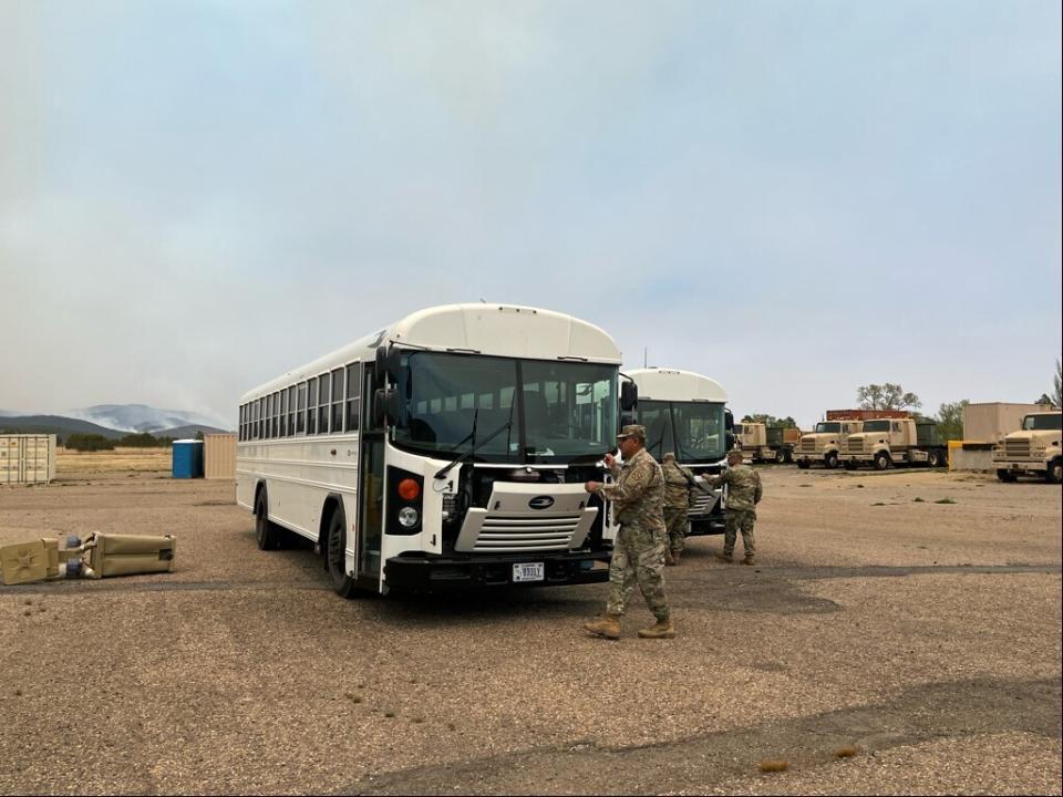 In this photo provided by the New Mexico National Guard, New Mexico National Guard soldiers on the ground ready buses to transport evacuees to emergency shelters established by the state at the Glorieta Center in response to the Calf Canyon/Hermits Peak fire in northern New Mexico on Sunday, May 1, 2022. Thousands of firefighters are battling destructive wildfires in the Southwest as more residents are preparing to evacuate. (New Mexico National Guard via AP)