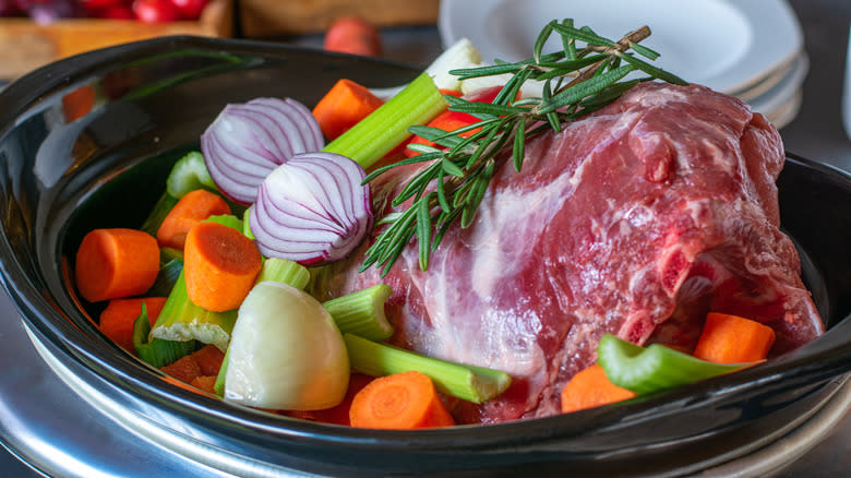 Raw roast and vegetables in slow cooker