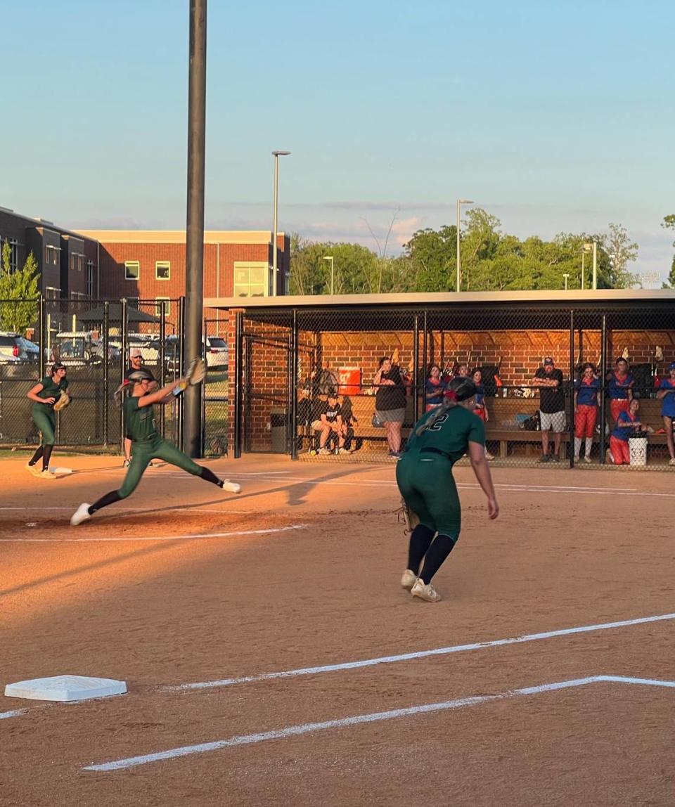 Catawba Ridge starting pitcher Chloe Burger (second green jersey from left) winds up to pitch while third base Audrey Wilson (12, green) creeps up to prepare to cover a bunt attempt.
