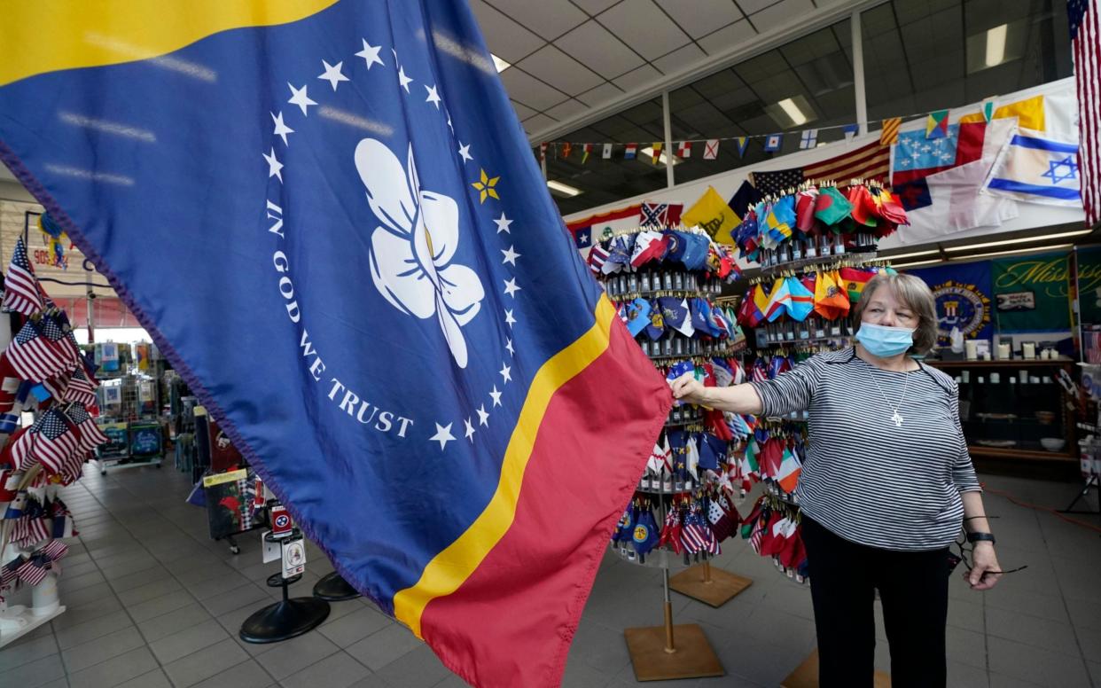 Brenda McIntyre, a co-owner of A Complete Flag Source store in Jackson, Miss., shows off the magnolia-centered banner chosen by the Mississippi State Flag Commission - Rogelio V. Solis/AP