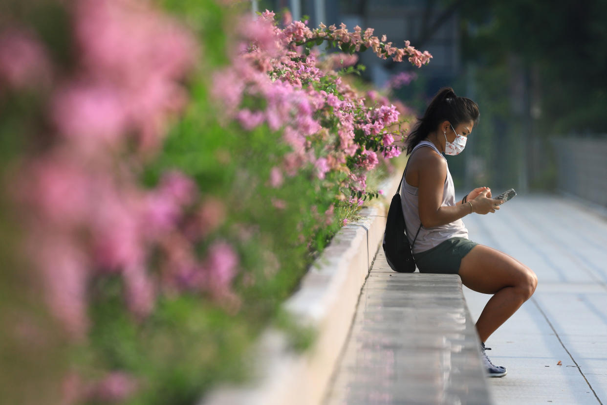 A woman wearing protective mask checks on her mobile phone on July 29, 2021 in Singapore.  (Photo by Suhaimi Abdullah/NurPhoto via Getty Images)