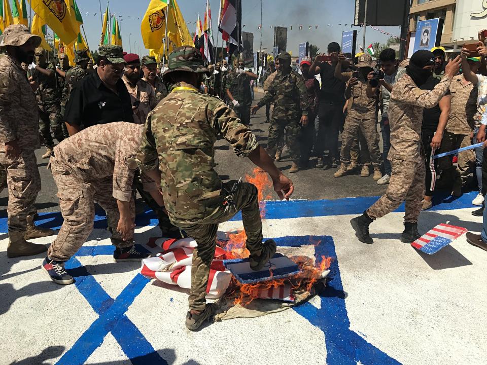 FILE - In this May 31, 2019 file photo, Iraqi Popular Mobilization Forces burn representations of U.S. and Israeli flags during "al-Quds" Day, Arabic for Jerusalem, in Baghdad, Iraq. Iran-aligned Shiite militias are posing an increasing challenge for Iraq ahead of key talks with Washington in early April 2021, that are meant to shape the future of the U.S.-Iraq relationship. (AP Photo/Ali Abdul Hassan, File)