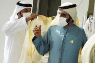 An aide puts a "bisht," or "cloak" in Arabic, around the shoulders of Dubai ruler Sheikh Mohammed bin Rashid Al Maktoum as he arrives at an event at Abu Dhabi Sustainability Week at Dubai Expo 2020 in Dubai, United Arab Emirates, Monday, Jan. 17, 2022. (AP Photo/Jon Gambrell)