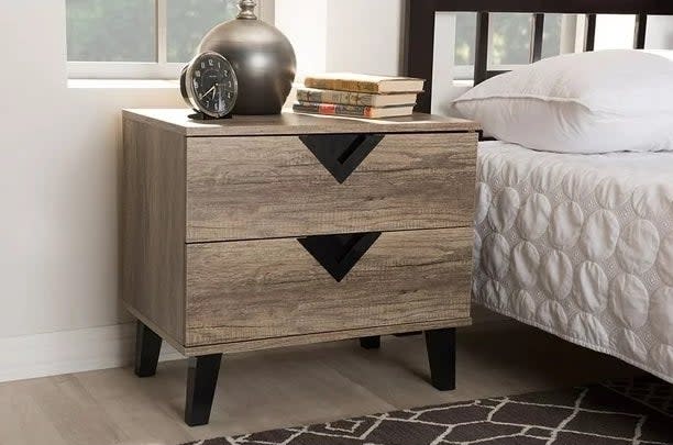 Wood nightstand next to a bed with white bedding