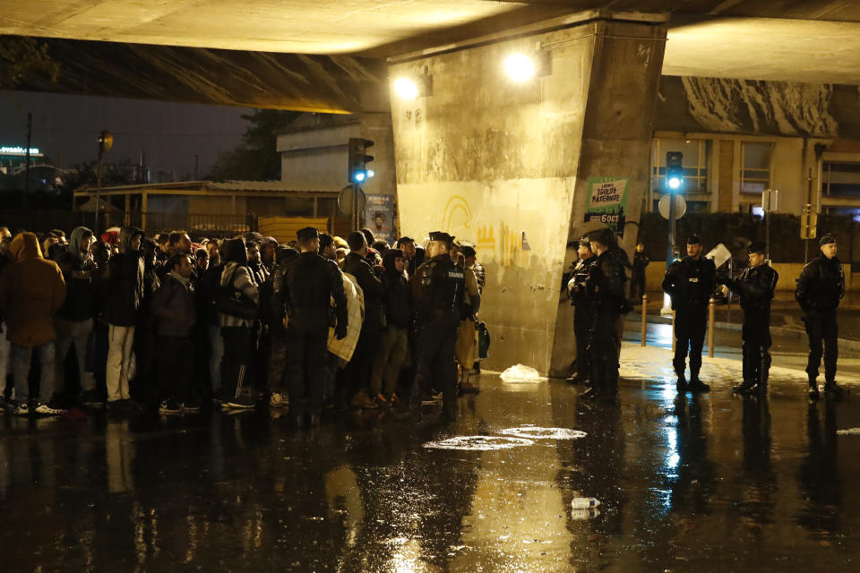 Police officers guard migrants as they clear an area Thursday, Nov. 7, 2019 in the north of Paris. Migrant encampments are becoming increasingly visible in the French capital. Police cleared Thursday several thousand people from a northern Paris neighborhood where migrants have repeatedly been removed. They are taken to shelters, and some eventually sent home. (AP Photo/Francois Mori)