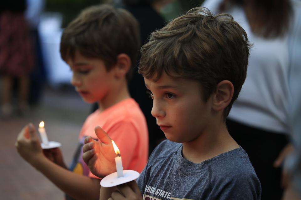 Grayson Brown (left) and brother Emmett Brown, both 7, look at their candles during a 2022 vigil at James Weldon Johnson Park in Jacksonville. People met in support of the Jewish community following recent displays of antisemitic messages.
