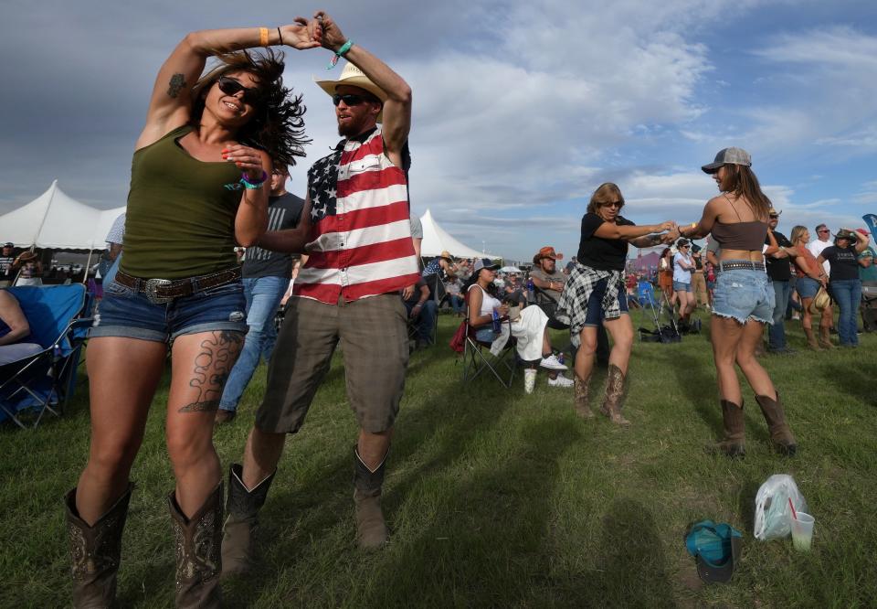 David Hatfield twirls his friend Dannielle Tyler as they dance at the Country Thunder Music Festival near Florence on April 13, 2023.