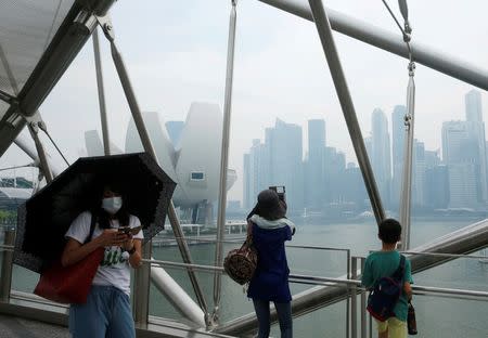 People pass the skyline of Singapore's central business district shrouded by haze August 26, 2016. REUTERS/Edgar Su