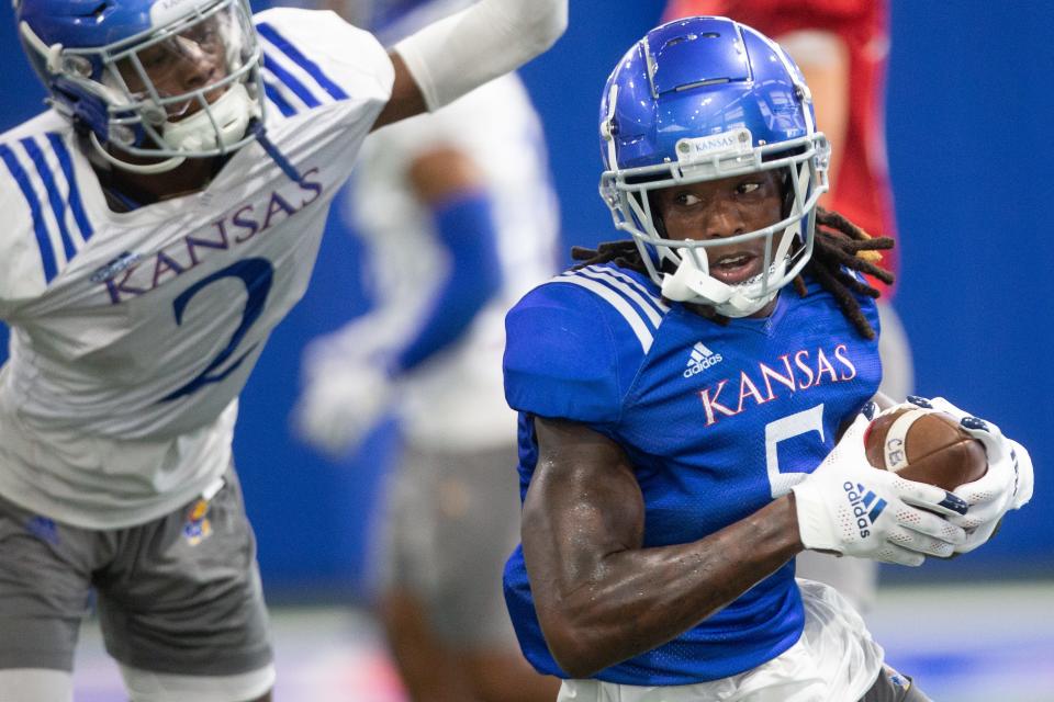 Kansas redshirt sophomore wide receiver Douglas Emilien runs through drills during a fall camp practice one evening this year at the indoor practice facility.