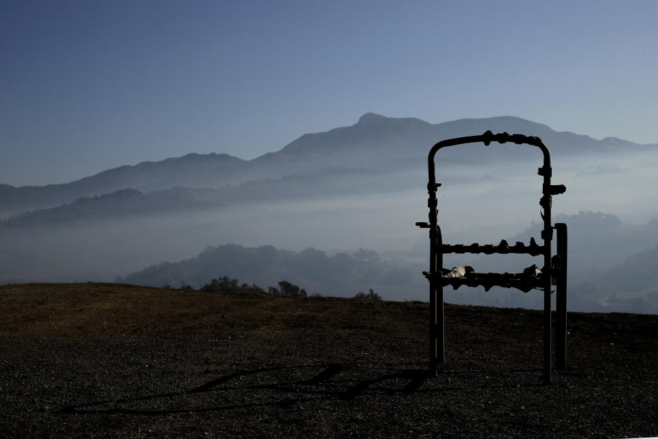 A charred lawn chair overlooks a valley filled with smoke from the Kincade Fire near Healdsburg, Calif., Nov. 1, 2019. (AP Photo/Charlie Riedel)