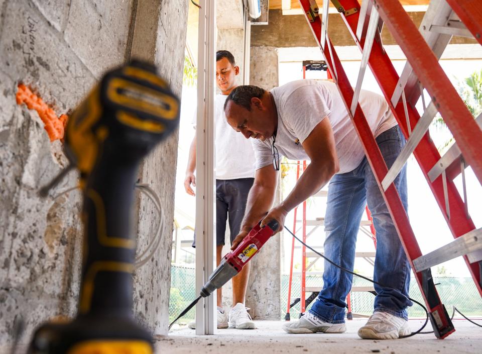 Orlando Rubio, right, and Jose Daniel Capote work on installing shutters on a home at Bay Colony in Naples.